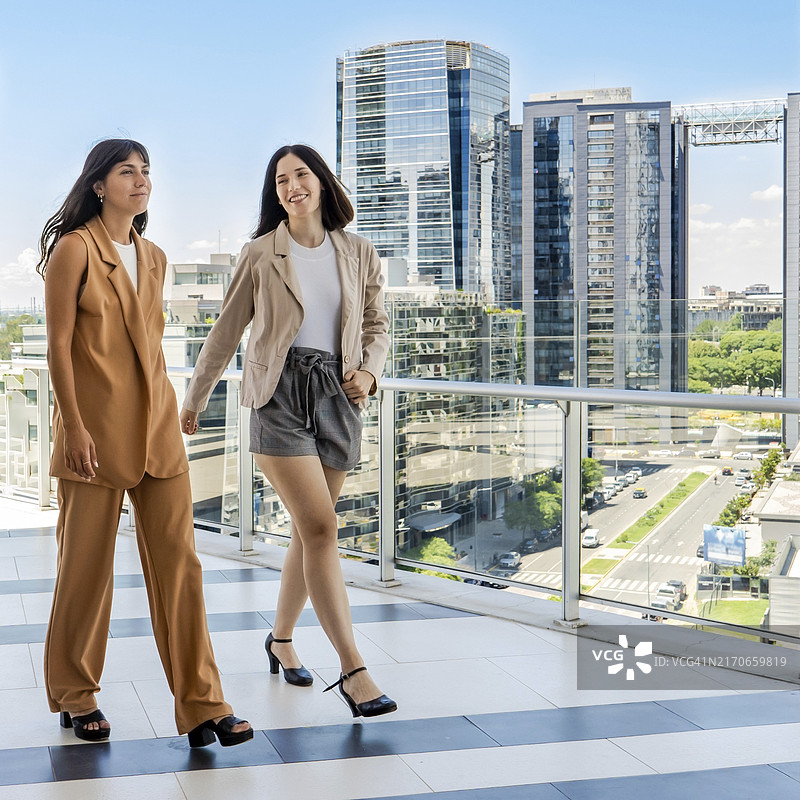 两位女商人于办公室露台上边走边交流图片素材