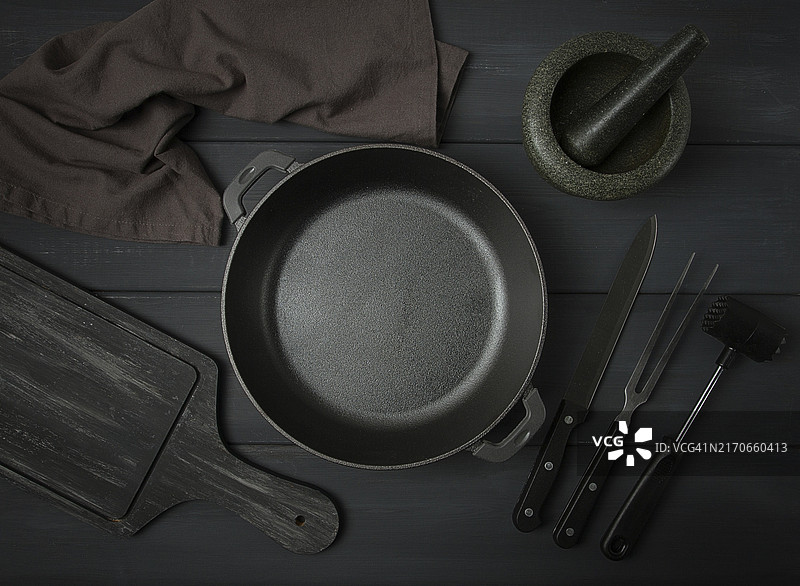 深灰色木桌上的铸铁烤炉和烹饪用具，俯视角度图片素材