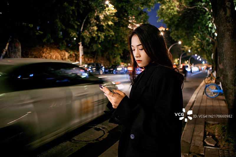 女商人下班后乘坐出租车并在城市街道上使用手机图片素材
