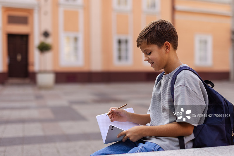 在教学楼前做作业的青少年男学生图片素材
