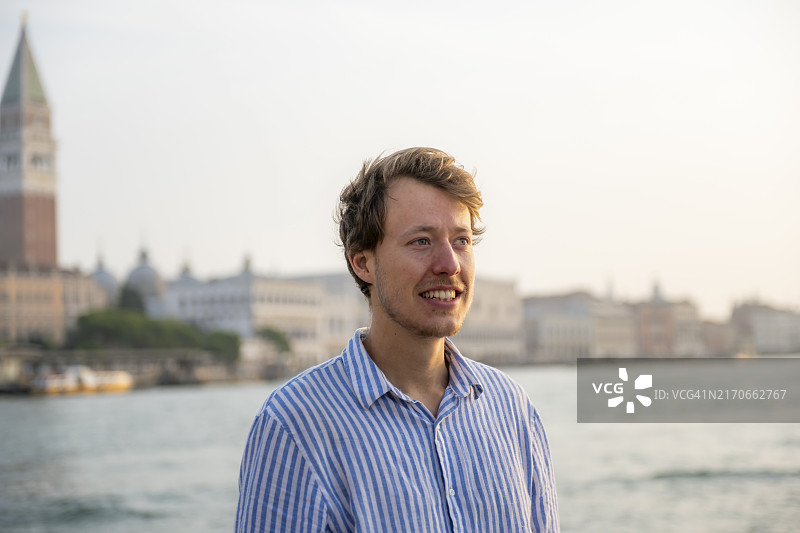 在意大利威尼斯大运河畔的条纹衬衫年轻人肖像图片素材