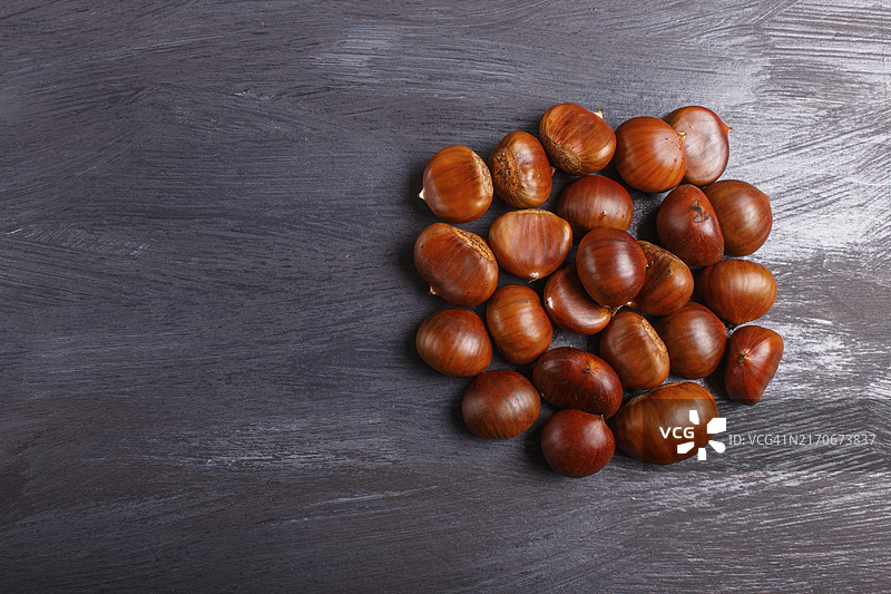 黑色木质背景上带复制空间的甜栗子堆，顶视图图片素材