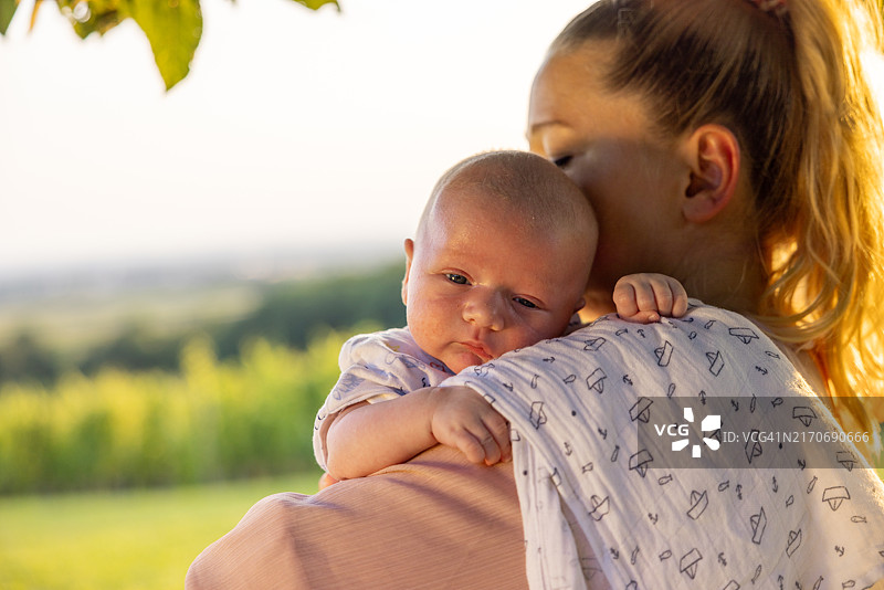 特写：慈爱的母亲在公园抱着新生儿子图片素材