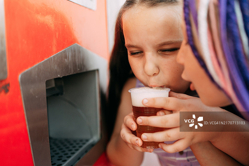 夏日街头从自动售货机购买汽水的女学生们图片素材