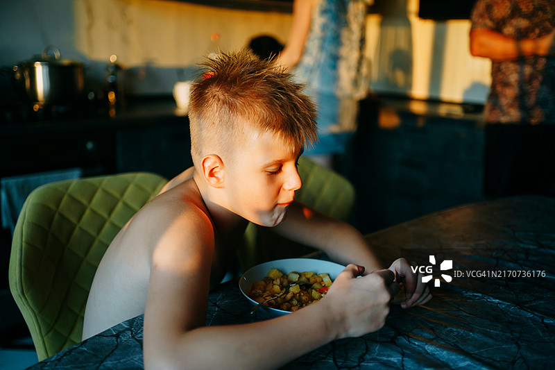 夏季傍晚，青少年在厨房的桌子旁吃东西图片素材