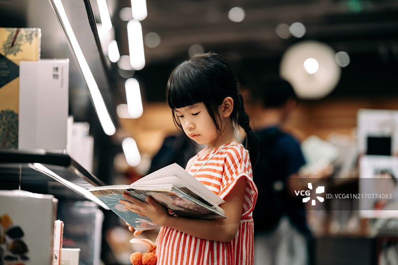 年轻亚裔女孩在书店看书，培养儿童良好阅读习惯图片素材