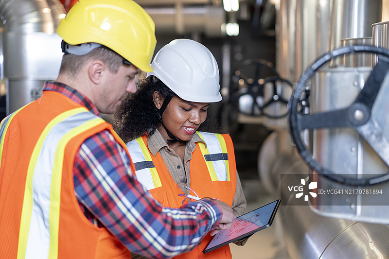 穿着安全设备在煤气管道旁行走并检查分配和消耗的工厂工人图片素材