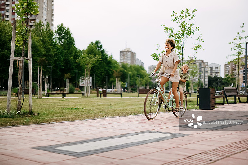 母亲在公园里骑自行车带着孩子图片素材