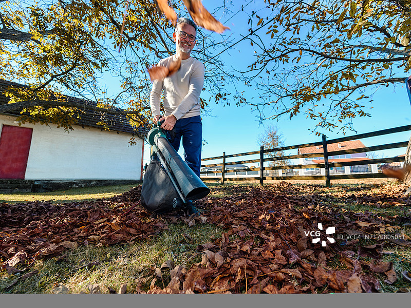 在院子里使用吹叶机的中年男人图片素材