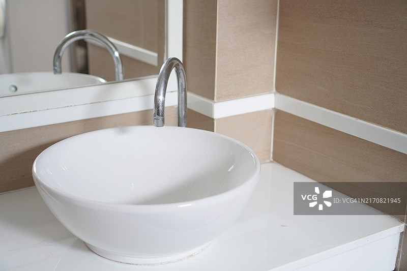 白色大理石台面上的洗脸盆和自动感应水龙头图片素材