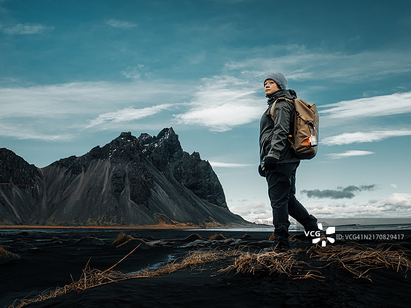 华人女子背着背包站在冰岛斯托克斯内斯半岛黑沙滩上的韦斯特拉霍恩山前图片素材