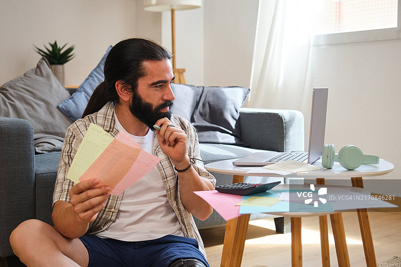 专注年轻男人远程工作核对家庭财务图片素材
