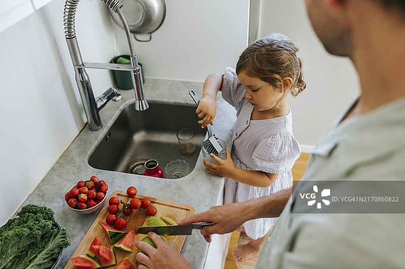 家中厨房女儿擦玻璃父亲切水果俯视图图片素材