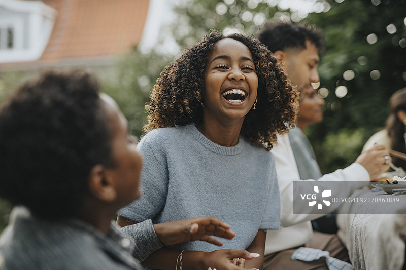 快乐卷发女孩与兄弟在后院社交聚会图片素材