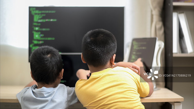 哥哥教弟弟使用笔记本电脑和大屏幕学习编程图片素材