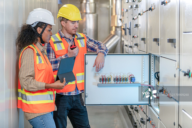 两位工程师在控制室工作并检查开关柜电气能量分配状态图片素材
