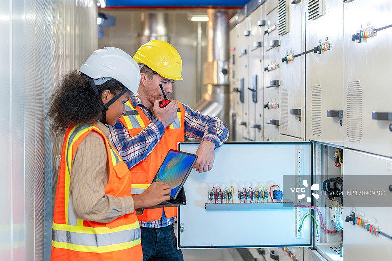 两位工程师在控制室工作并检查开关柜电气能量分配状态图片素材