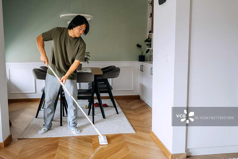 帅气的男人在家里打扫地板图片素材