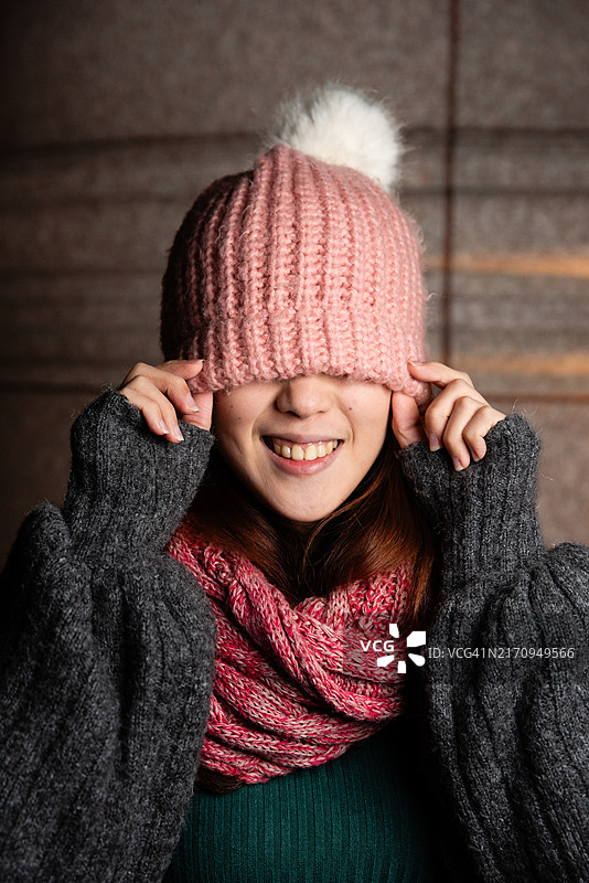 戴着毛皮帽子遮住眼睛的年轻女人像图片素材