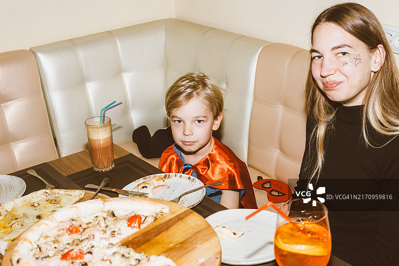 万圣节：年轻妈妈和儿子在披萨店共度美好时光图片素材