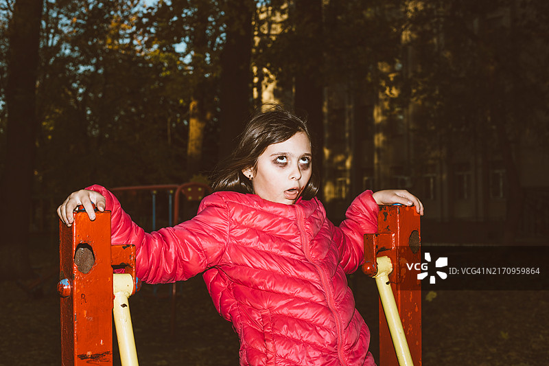 小女孩化着万圣节风格的彩绘在操场玩耍图片素材