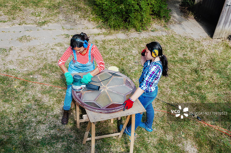 母亲和十几岁的女儿在花园里一起改造旧窗户图片素材