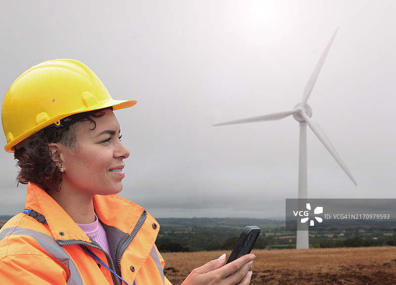 女工程师在风力涡轮机旁使用手机图片素材