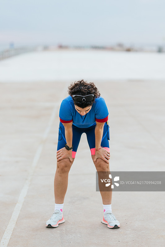 训练后跪在地上休息的疲惫女跑步者图片素材