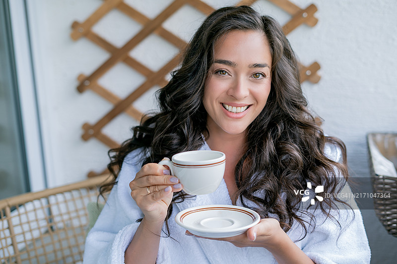 年轻黑发女子在舒适阳台上喝咖啡图片素材