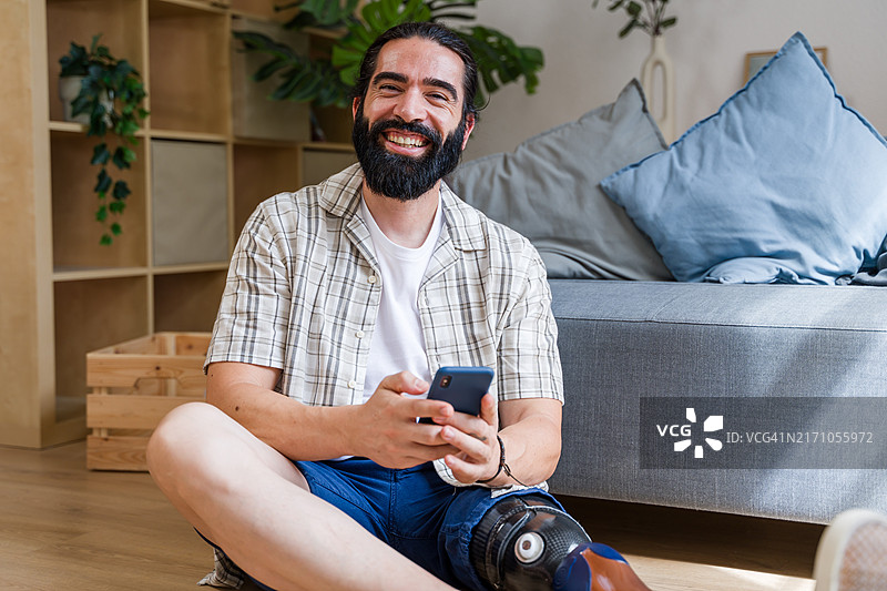 微笑着的腿部受伤在家使用智能手机的男人图片素材