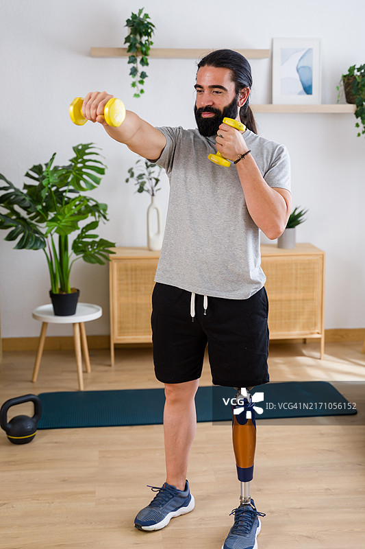 在家用哑铃锻炼的年轻截肢男子图片素材