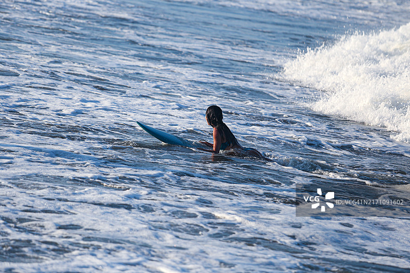 在冲浪板上等待海浪的女孩图片素材
