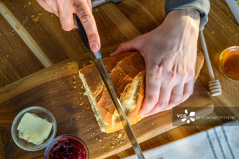 在木质表面上切抹黄油、果酱和蜂蜜的面包图片素材
