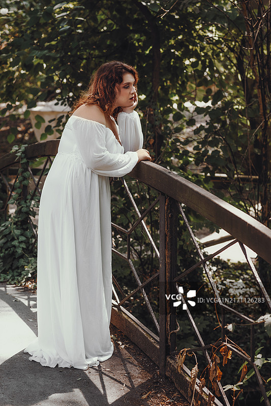 站在桥上，面带忧伤的年轻女子肖像图片素材