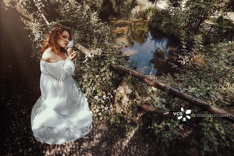 在池塘边白日梦的优雅年轻女子肖像图片素材
