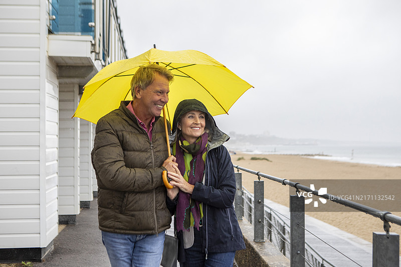 一对中年夫妇在海边雨中漫步图片素材