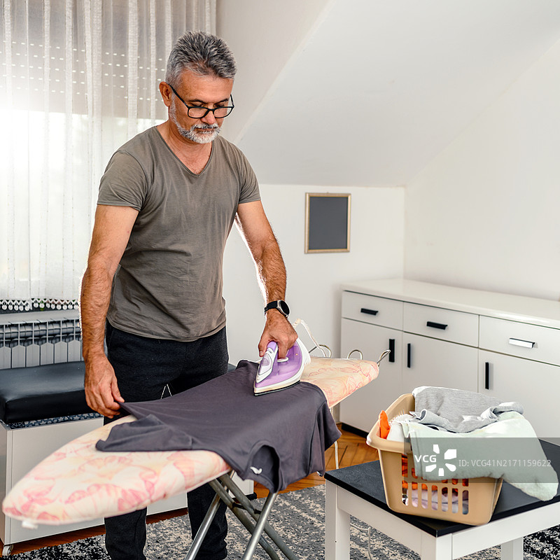 在家熨烫衣服的中年男人图片素材