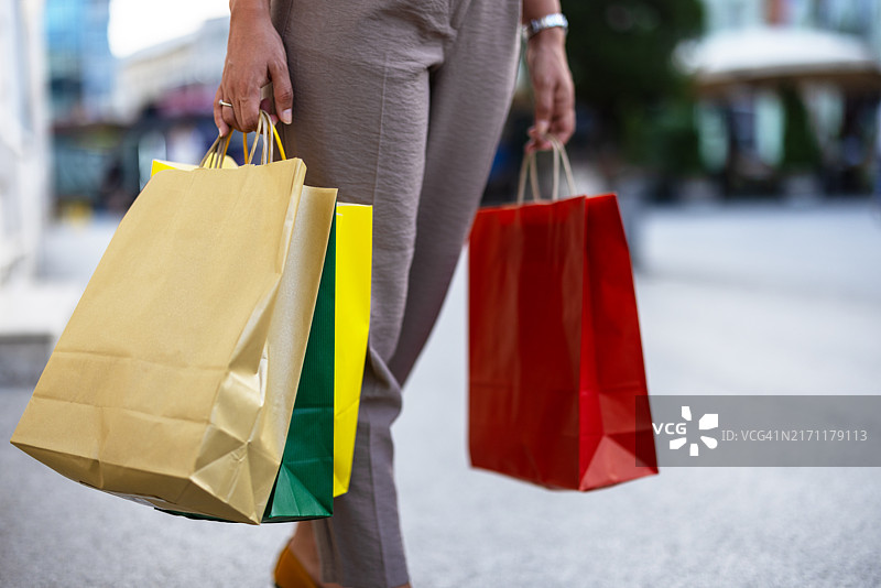 女人手提购物袋走在城市里图片素材