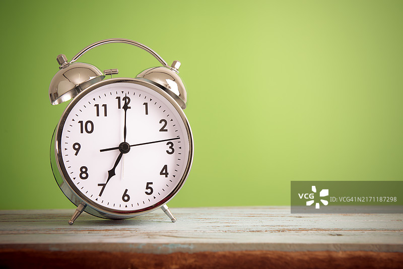 绿色背景的桌子上闹钟的特写图片素材
