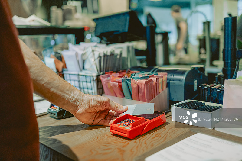 模糊男子使用信用卡在读卡器上支付图片素材