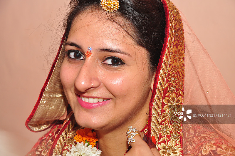 面带微笑的漂亮女人穿着纱丽靠在墙上图片素材