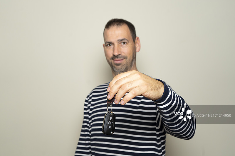 年长的西班牙裔男子，留着胡须，穿着条纹毛衣，拿着车钥匙图片素材