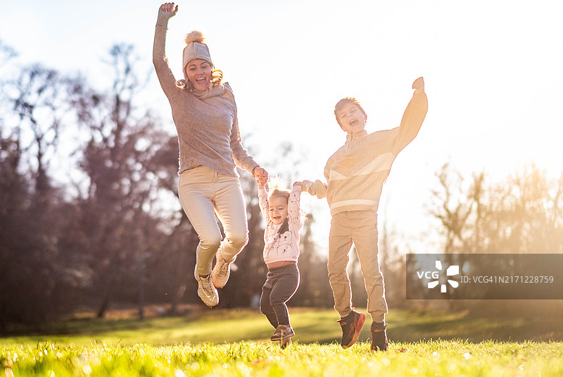 在草地上一起跳跃的家庭图片素材