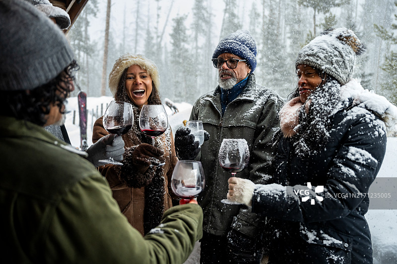 在冬季小屋外碰杯的多种族朋友们图片素材