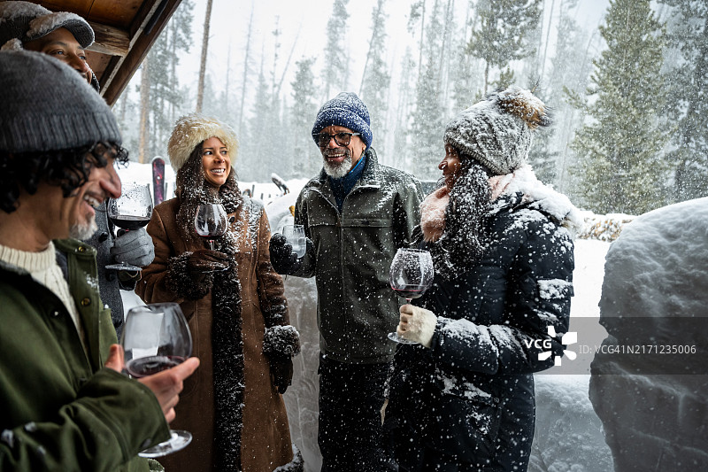 年长的非洲裔美国男人在冬季小屋外与朋友们微笑图片素材