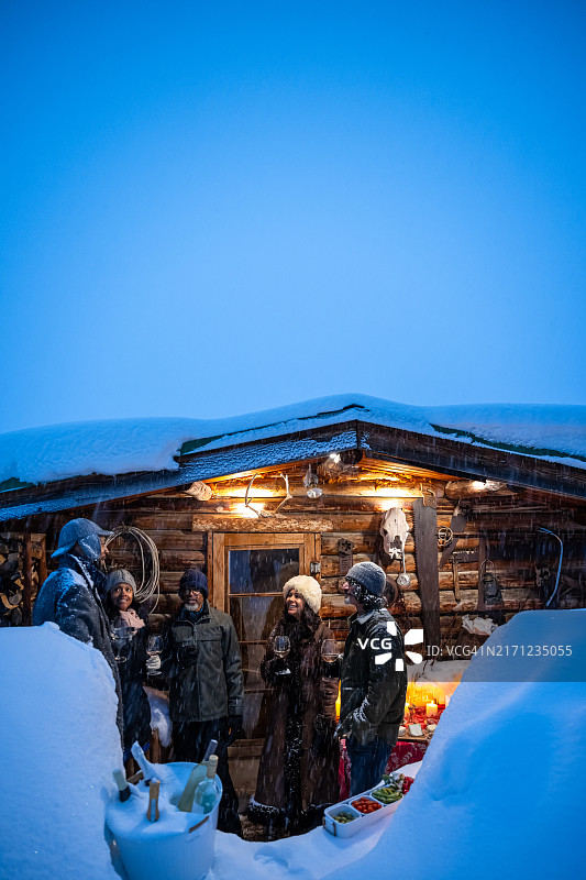 竖版：五个多种族朋友在小木屋外晚上喝酒图片素材