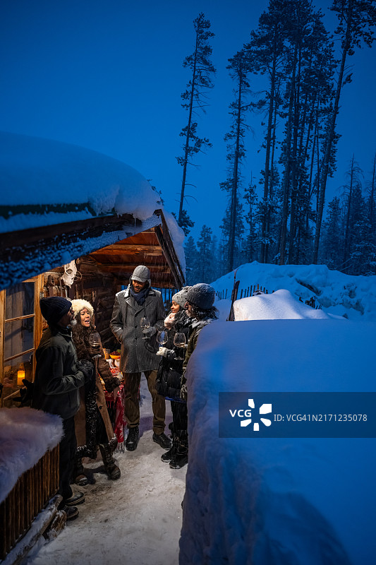 雪夜小木屋前快乐的朋友们（竖版照片）图片素材