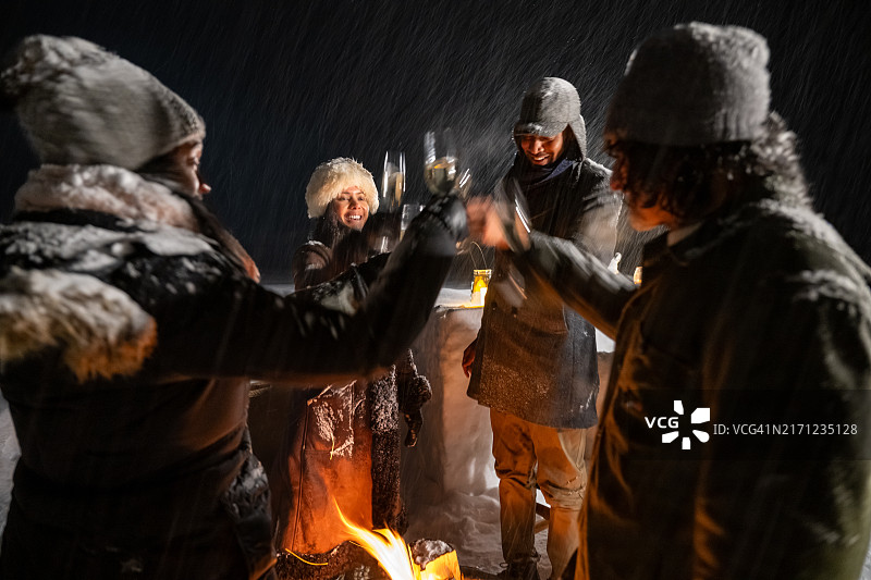 雪夜篝火旁多种族朋友举杯庆祝图片素材