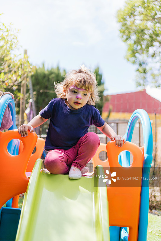 在户外游乐场上玩耍的彩绘脸女孩，享受阳光明媚的一天图片素材