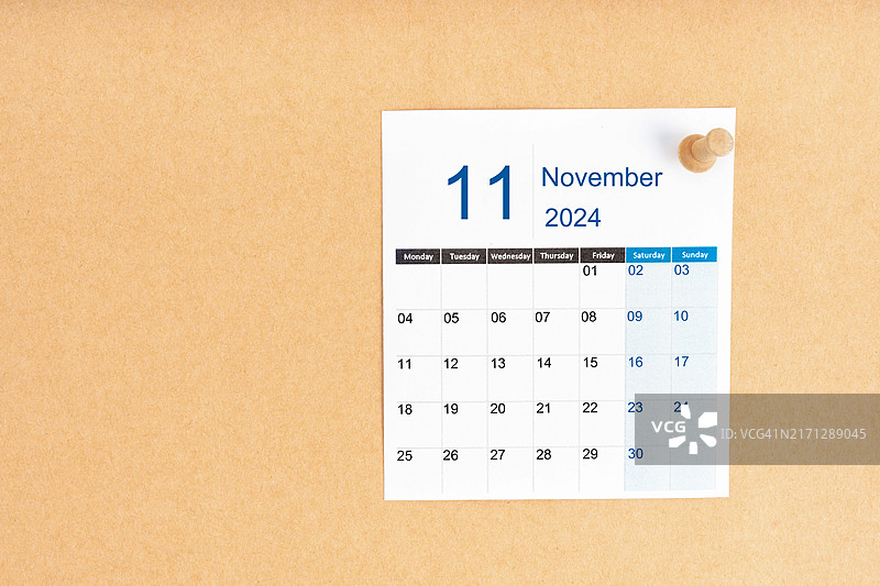 棕色背景上的2024年11月日历与木制图钉，留有复制空间图片素材